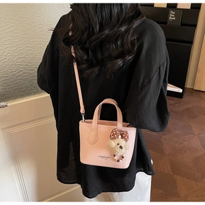 Pink lychee texture tote bag with teddy bear charm shown in a cozy interior setting