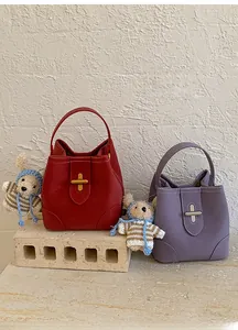 Detail of lychee pattern leather bucket bags in red and purple with bear charms