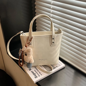 Detail of cream white tote bag with MIAOSHE text logo and blue plush bear charm
