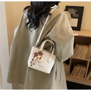 Detail of white lychee leather handbag with shoulder strap and plush bear charm