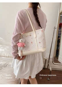 Detailed back view of a white cartoon print tote bag with a cute bear plush keychain accessory