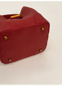 Detail of red pebbled leather bag base with four protective gold metal feet studs
