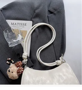Chic white dumpling bag with unique knot shoulder strap and plush bear charm detail