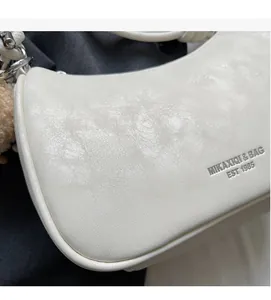 Detailed close-up of white embossed leather handbag with MIKAXIQI logo and soft texture