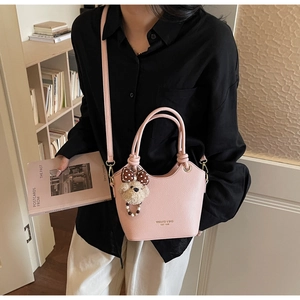 Detail of pink leather bucket bag with plush bear charm and elegant gold logo