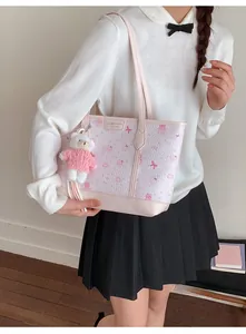 Detailed view of pink cartoon tote bag with leather trim and plush bear charm