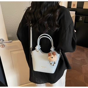 Detail of light blue bucket bag with plush bear charm and adjustable shoulder strap