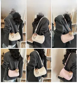Detail view of retro crescent shoulder bag in beige and pink with plush bear charm