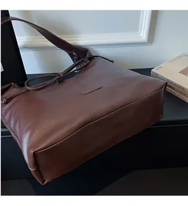 Detailed view of dark brown tote bag showing the soft pebbled leather texture and strap