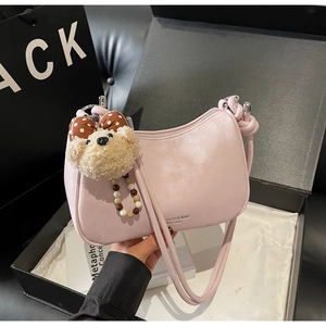 Detail of pink dumpling bag with plush bear charm and bow, displayed as a luxury gift