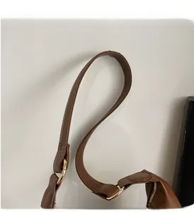 Detail of dark brown leather shoulder strap with gold metal rings and zipper closure