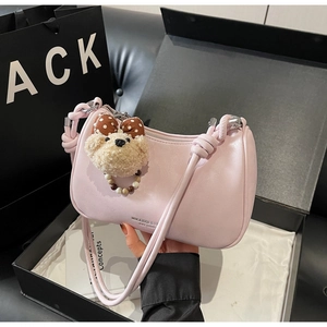 Detail of pink PU leather crescent bag with knot strap and plush bear charm in gift box