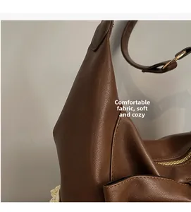 Detail of soft brown pebble leather shoulder bag with gold buckle and smooth zipper