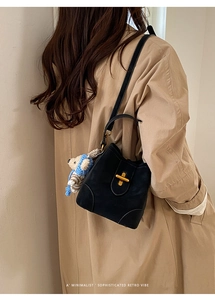 Detail of black pebbled leather bucket bag with gold lock and cute bear charm pendant