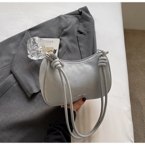 Detail of light grey crescent bag featuring a knotted strap and silver metal hardware