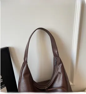 Detailed macro view of dark coffee hobo bag with leather texture and silver zipper detail