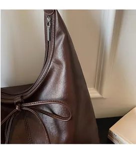Detail of soft brown leather Hobo bag with stylish bow accent and silver side zipper closure