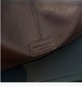 Detailed macro view of deep brown leather texture and embossed logo with fine stitching