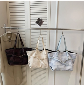 Close-up of three canvas tote bags in chocolate, beige, and blue on a hanger