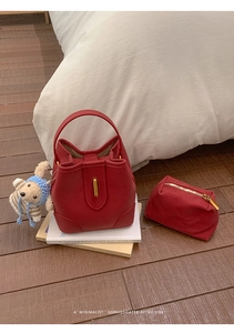 Deep red leather bucket bag set with matching pouch and cute bear pendant on a neutral background