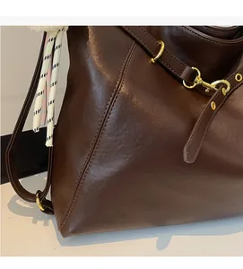 Detail of dark brown leather tote featuring refined stitching and premium gold hardware