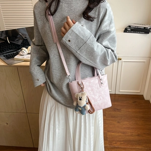 Pink faux leather bucket bag with cute bear charm shown in cozy lifestyle setting