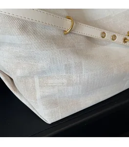 Detail of soft cream knitted fabric with gold hardware and beige leather strap on tote bag