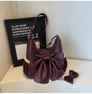 Detail view of burgundy bow shoulder bag featuring white lace trim and adjustable straps