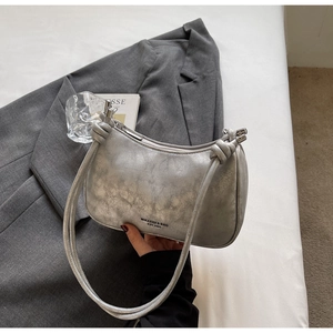 Detail of silver metallic crescent bag with knotted shoulder strap and zipper closure