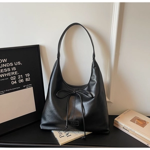 Detail of minimalist black leather hobo bag with a soft matte texture and bow tie design