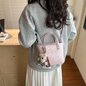 Detail of pink leather bucket bag with silver logo and cute bear plush charm accessory