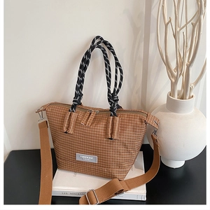 Detail of checkered tote bag with knot handles, woven label, and adjustable strap