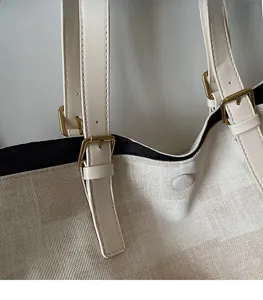 Detail of adjustable shoulder strap with golden buckle on textured beige tote bag