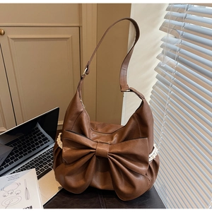Detailed close-up of dark brown crescent bag with large bow and white lace trim