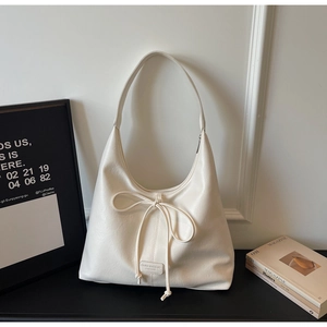 Detail of hobo bag featuring decorative bow drawstring and embossed logo on matte leather
