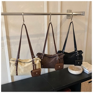 Three shoulder bags in beige, brown, and black with detachable coin pouches and studs