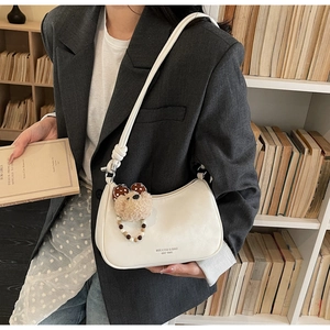 Detail of ivory leather dumpling bag with brand logo and cute plush bear charm