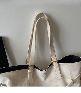 Detail of adjustable leather strap and textured canvas material on large beige tote bag