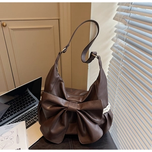Detail of dark brown shoulder bag with large bow, lace trim and soft faux leather texture
