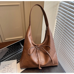 Detail of a brown PU leather shoulder bag featuring a decorative bow and brand label