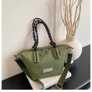 Close-up of green checkered handbag featuring black and white woven rope handles