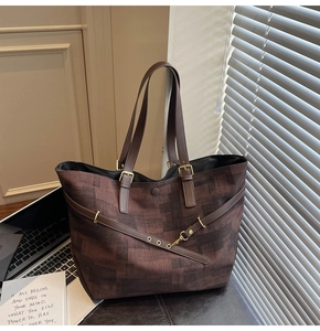 Detail of vintage brown patterned tote bag featuring leather straps and buckle accents