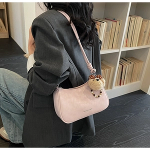 Pink dumpling style shoulder bag featuring a cute plush bear charm with bow detail
