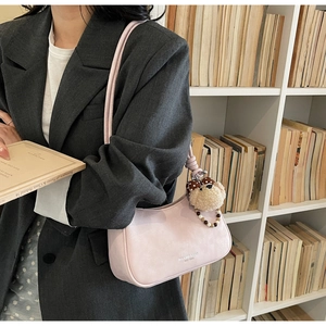 Chic light pink hobo bag detail with gold branding and cute teddy bear pearl charm