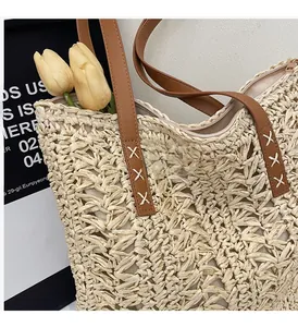 Detail of hand-woven straw tote with brown leather strap and sturdy cross-stitch seams