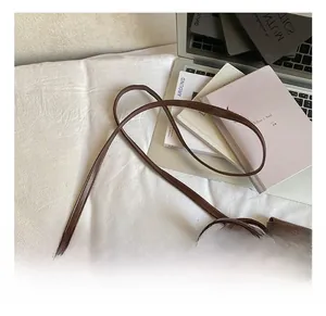 Detail showing the adjustable leather shoulder strap and metal buckle of the brown bag
