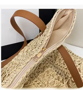 Close-up of golden zipper and fine woven texture on beige straw tote bag details