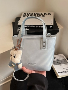 Light blue mini bucket handbag with plush bear charm and crossbody strap for women