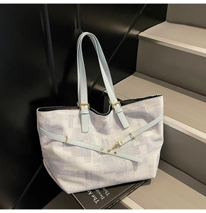 Close-up of geometric print tote bag with blue leather straps and gold hardware