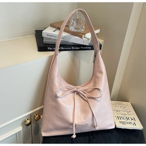 Detail of pink crescent bag with bow decoration and smooth matte leather texture